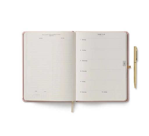 Open planner with a pen on a white background