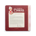 A square hardcover book titled '12 Days of Cookies: A Note from Mrs. Claus' by Demaco, featuring a dark red textured cover with a white central label containing a holiday message and an illustration of Mrs.
