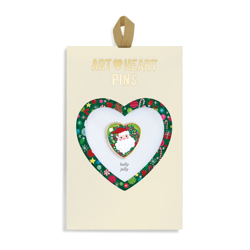 Heart-shaped art pin with 'holly jolly' design on a branded card.