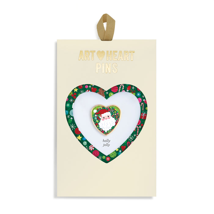 Heart-shaped art pin with 'holly jolly' design on a branded card.