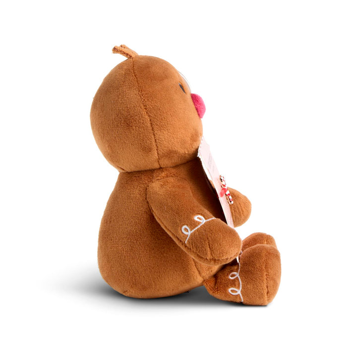 A brown plush toy shaped like a gingerbread figure, shown from the back while holding a white paper tag, on a clean white background.