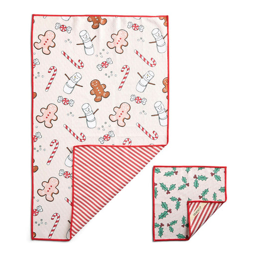 A set of two folded holiday-themed cloth napkins on a white background. The larger napkin features a festive print with gingerbread men, snowmen, candy canes, and marshmallows on a cream background with a red border.
