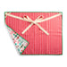 A square red holiday-themed cloth napkin with vertical red and white stripes, a green border, a cream ribbon tied in a bow, and a folded corner showing a white reverse side with colorful candy illustrations.