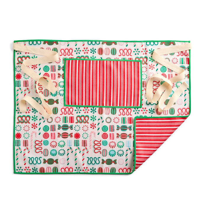 A square Christmas-themed fabric gift wrap or gift bag shown flat on a white background, with one corner folded over to reveal the reverse side. The front features a white base printed with red and green candy motifs, a red-and-white striped central panel, and cream ribbon laces tied at the corners.