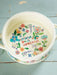 Decorative pot with floral design and 'Happiness is Homemade' text on a blue wooden surface