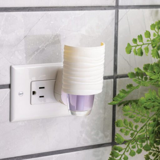 Decorative night light attached to a wall socket with a plant in the background