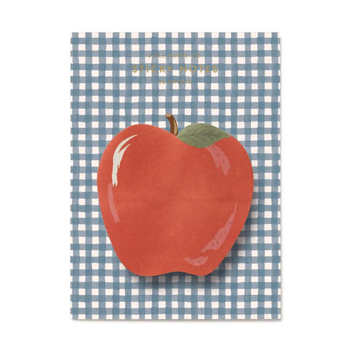 A square greeting card featuring a large red apple with a green leaf on a blue and white gingham checkered background. The top has gold foil text that reads 'Happy Teacher's Day!'.