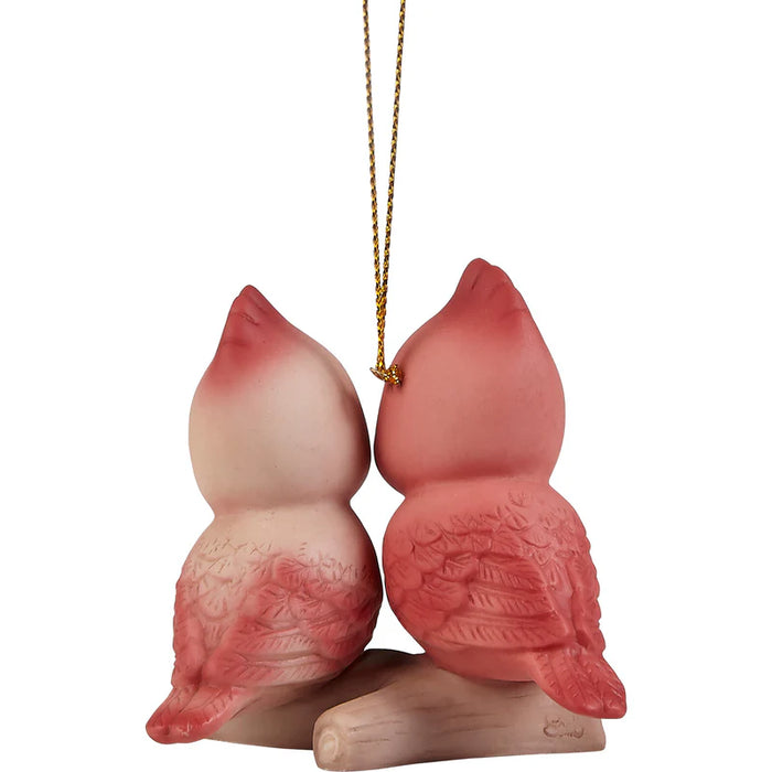 A decorative hanging ornament shaped like two pink-and-peach birds facing each other on a small branch, suspended by a gold string against a plain white background.