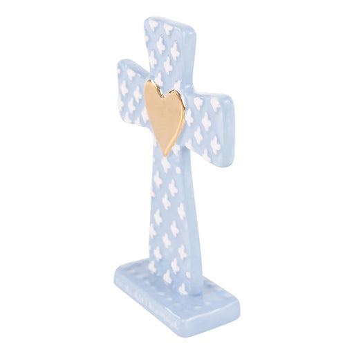 Decorative cross with a gold heart on a light blue stand against a white background