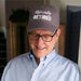 Man wearing a cap with 'Officially RETIRED' text, indoors.