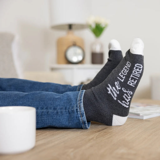 Person wearing socks with text, sitting on a couch in a living room.