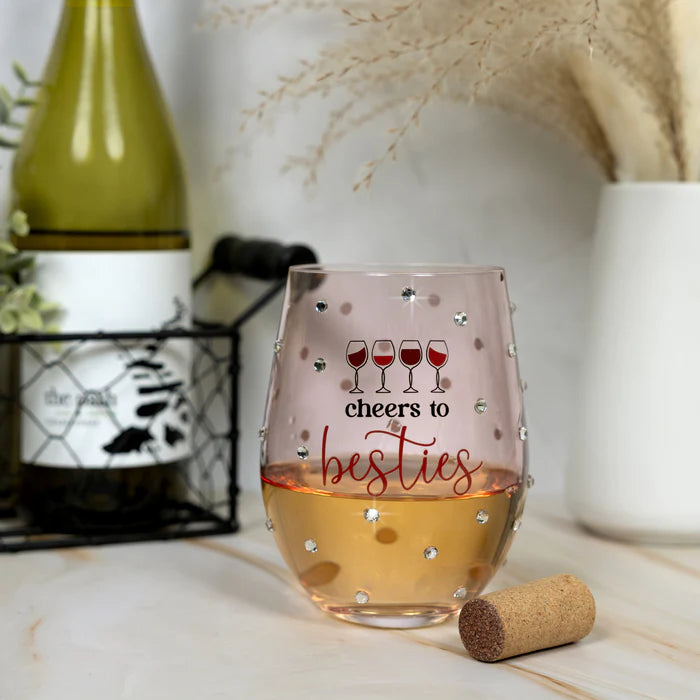 Stemless wine glass with 'cheers to besties' text and wine bottle in the background