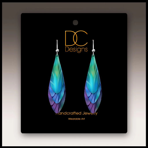 Colorful feather-shaped earrings on a black card with 'DC Designs' branding.