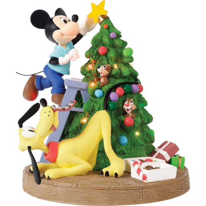 Animated character figurine decorating a Christmas tree with presents and a star.