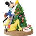 Animated character figurine decorating a Christmas tree with presents and a star.