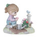 Figurine of a girl watering flowers with a birdhouse in the background