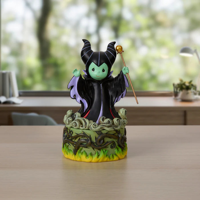 Figurine of a character with green skin and black outfit on a decorative base, held by a hand.