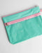 Turquoise pouch with pink zipper on a light gray background
