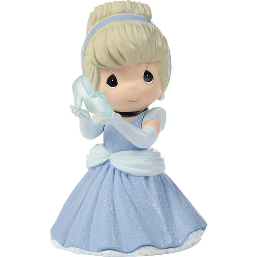 Toy figure of a girl in a blue dress holding a glass slipper on a white background