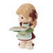 Figurine of a girl holding cookies with '2026' on an apron against a white background