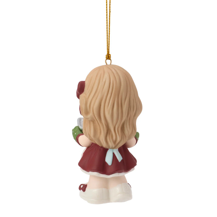 A small hanging ornament shaped like a child from the back, with long blonde hair, a burgundy dress, green sleeves, and white shoes, suspended by a gold string on a plain white background.