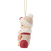 A Christmas ornament shaped like a baby doll wearing a cream knit hat with a white pom-pom and a red-and-cream sweater, holding a small dog, hanging from a gold string on a white background.