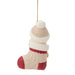 A Christmas stocking ornament shaped like a person wearing a cream cable-knit stocking, a beige knit beanie with a white pom-pom, and a red cuff, hanging by a gold string against a white background.