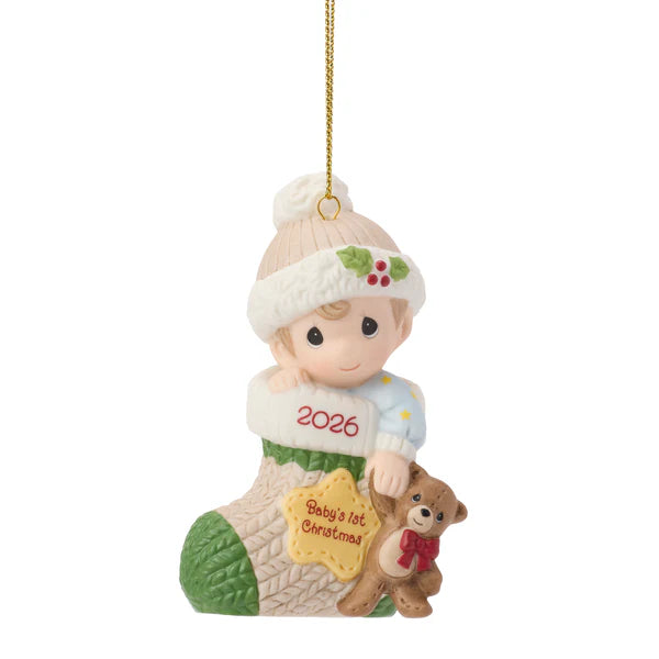 Christmas ornament of a child in a stocking with '2026 Baby's 1st Christmas' text, holding a teddy bear.
