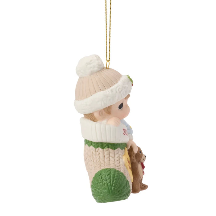 Decorative Christmas ornament of a child in winter clothing with a teddy bear, hanging on a white background.