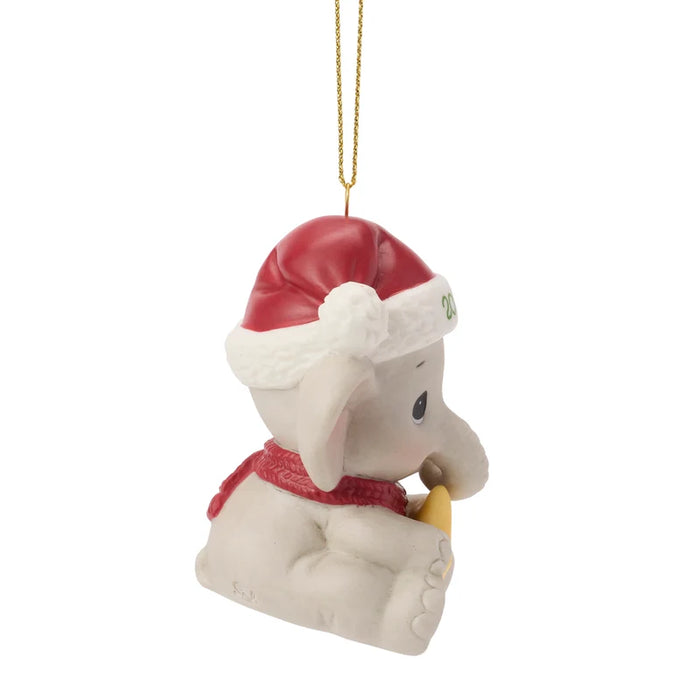 Christmas ornament of a elephant wearing a Santa hat and holding a present on a white background
