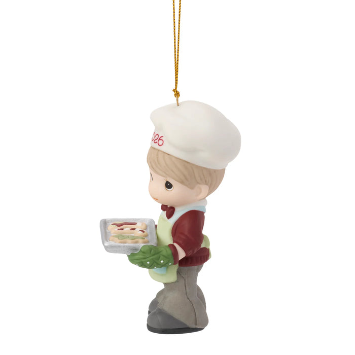 Christmas ornament of a boy holding a tray with cookies, wearing a chef's hat and coat.