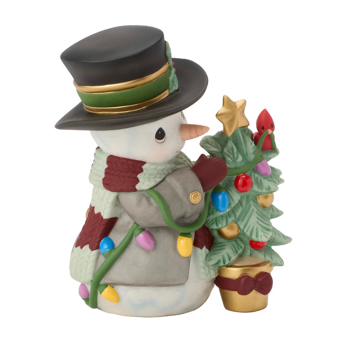 Decorative snowman figurine with a small Christmas tree on a white background