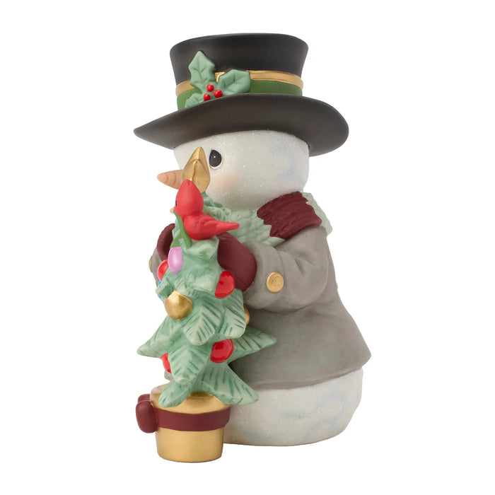 Decorative snowman figurine holding a small Christmas tree on a white background