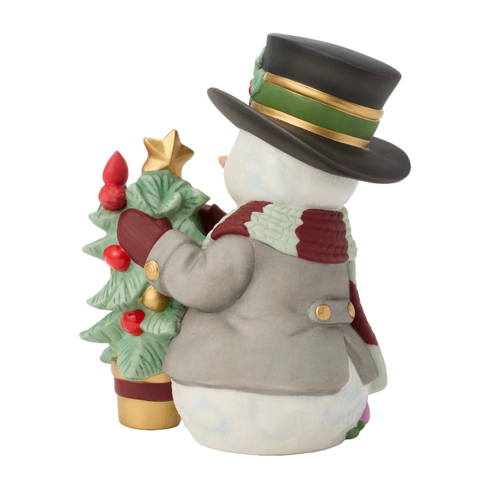 Snowman figurine decorating a Christmas tree with a top hat and scarf on a white background