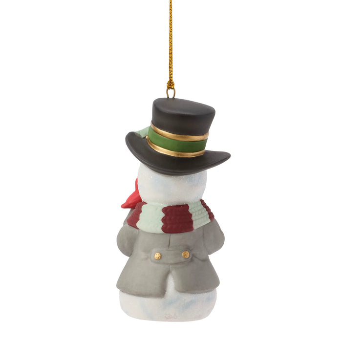 A snowman Christmas ornament wearing a black top hat with a green and gold band, a gray coat, and a red and white striped scarf, hanging by a gold string against a white background.