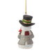 A snowman Christmas ornament wearing a black top hat with a green and gold band, a gray coat, and a red and white striped scarf, hanging by a gold string against a white background.