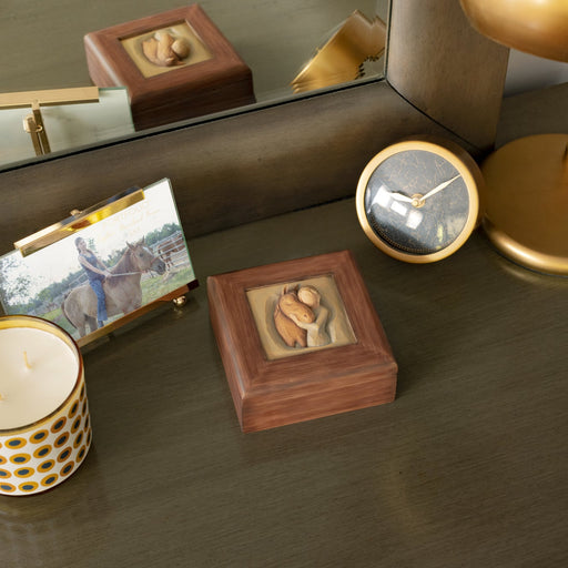 Reddish-brown square wood box with hinged lid: Carving of girl in green dress, with arms embracing reddish-color horse on lid of box
