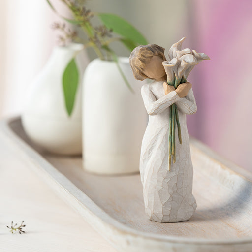 Decorative figurine of a woman holding flowers on a surface with blurred background