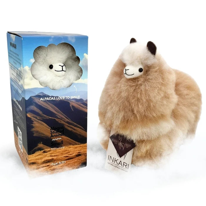 A fluffy alpaca plush toy next to its retail box. The plush is cream and tan with black ears and a small white patch on its face.