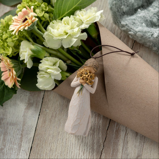 Figure in cream dress, holding large bouquet of yellow sunflowers up to face. Hook and loop affixed to figure's head
