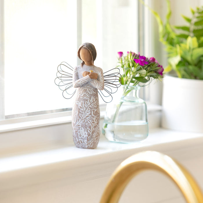 Figure with darker skin and hair, arms crossed over gold heart, in dress carved with icons of remembrance and nature
