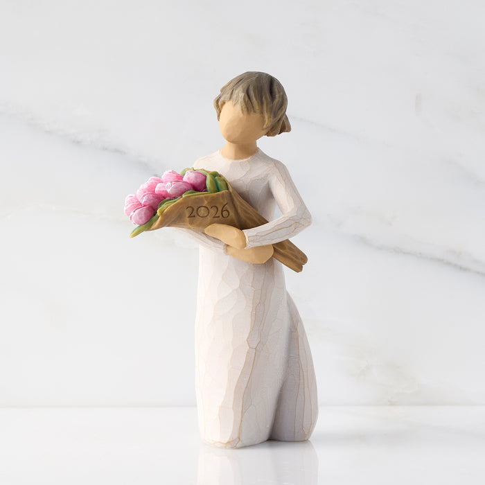 Figurine of a woman holding flowers with '2026' on a white background
