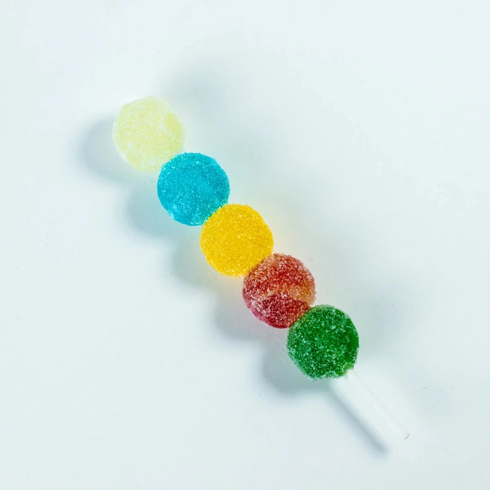 Colorful gummy candy on a stick against a white background