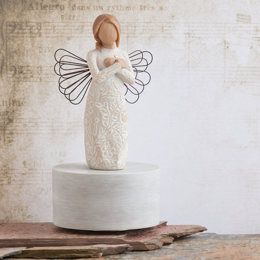 Ceramic angel figurine with wire wings on a textured surface