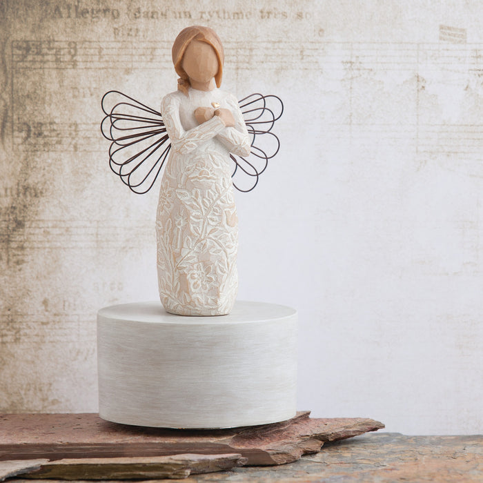 Ceramic angel figurine with wire wings on a textured surface