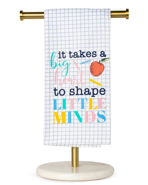 Towel with educational quote and apple graphic on a stand against a white background