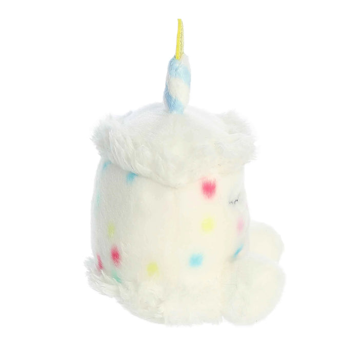 Plush toy resembling a birthday cake with a unicorn horn on a white background
