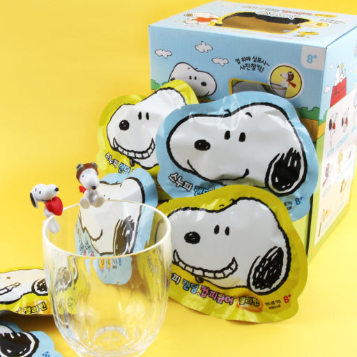 Snoopy-themed products including a glass and packaging on a yellow background
