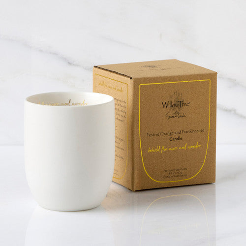 White candle next to its brown cardboard box on a white background