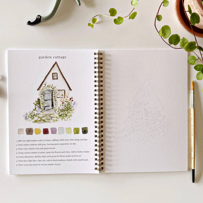 Open book with garden-themed illustration and color swatches on a white surface with greenery.